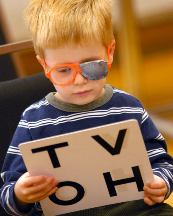 Child having his eyes tested with a patch on his glasses